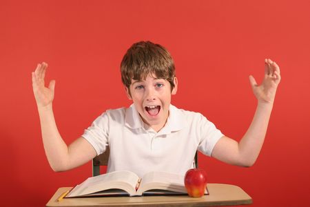 young boy at desk with hands upの写真素材