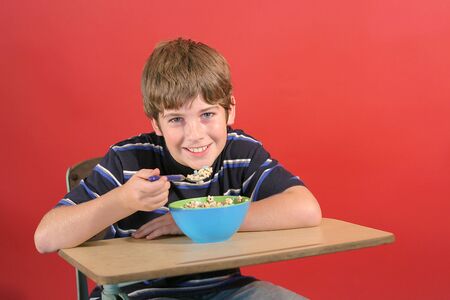 kid eating cereal at deskの写真素材