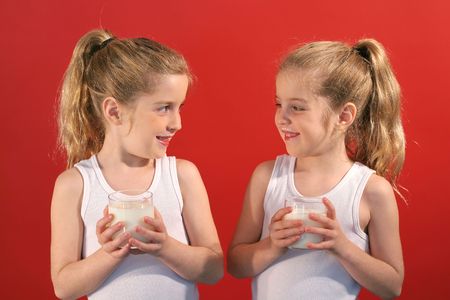 twin children drinking a glass of milkの写真素材
