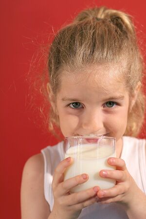 happy little girl drinking milkの写真素材