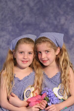 identical twin sisters holding flowersの写真素材