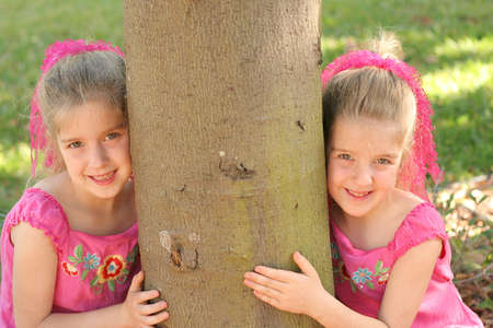 twin girls hugging the treeの写真素材