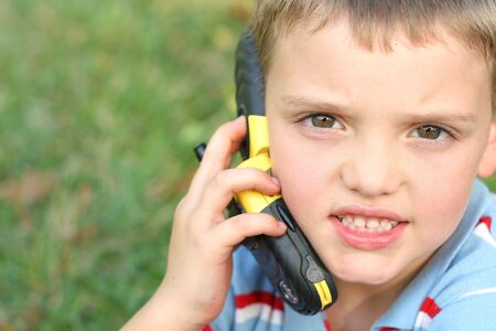 cute little boy on cell phone outsideの写真素材