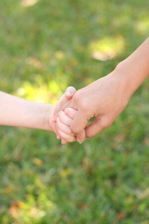 holding childs hands in grass verticalの写真素材