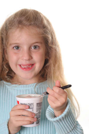 happy little girl eating yogurt verticalの写真素材