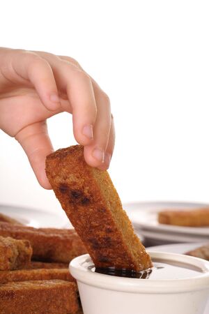 young child dipping french toast in syrupの写真素材