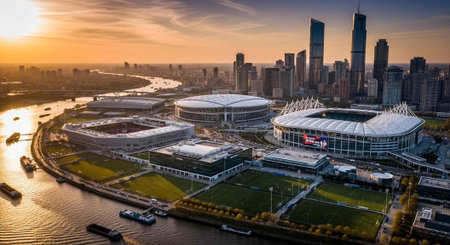 Aerial view of a modern sports stadium complex at sunset in a bustling cityscape with a river