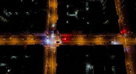 Aerial view of a city intersection at night with traffic, emergency vehicles, and streetlights...