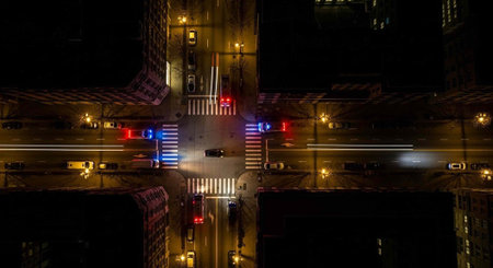 Aerial view of a city intersection at night with a police car and traffic lights