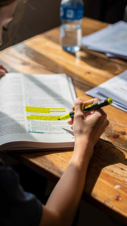 Close up of a woman writing in a notebook on a wooden table