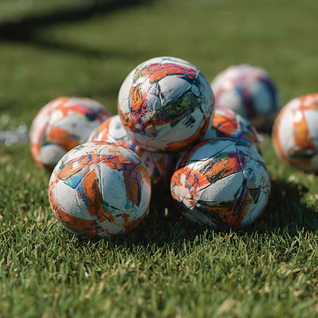 A group of soccer balls on the grass of a soccer field.