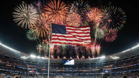 American flag with fireworks in the stands of the stadium at night.