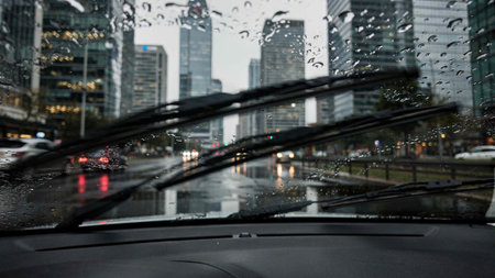 Rain drops on car windshield in city. Rainy day. Shallow DOF