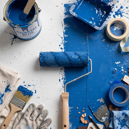 Paint roller and paint brushes on a blue background, top view