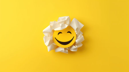 Smiling emoticon made of crumpled paper on yellow backgroundの素材