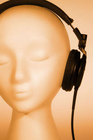 Female mannequin head listening to music with orange overlayの写真素材