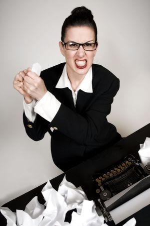 Retro business woman with vintage typewriter crumpling a paperの写真素材