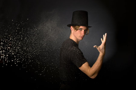 Young male magician throwing magic powderの写真素材