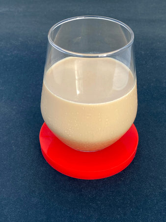 Iced latte drink with red coaster standing on black table