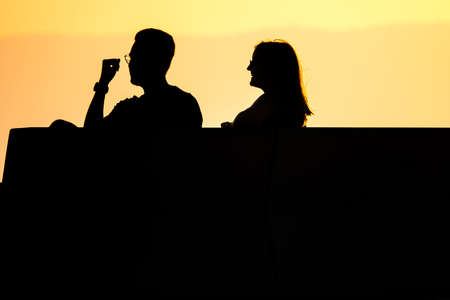 Young couple, man and woman talking eachother against the sky - silhouetteの写真素材