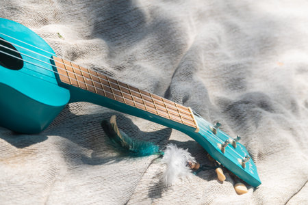 Close up turquoise color ukulele guitar neck on linen cloth background on sunny weather