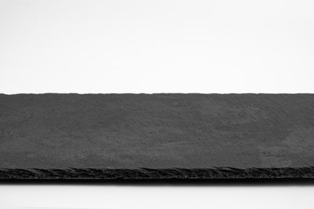 Slate plate isolated on white background. Empty stone tray for food.の写真素材