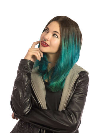Beautiful girl looking upward and thinking on a white background. Pierced, turquoise haired and dressing a leather jacket.の写真素材