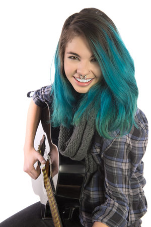 Beautiful smiling girl playing guitar on a white background. Pierced, turquoise haired and dressing...