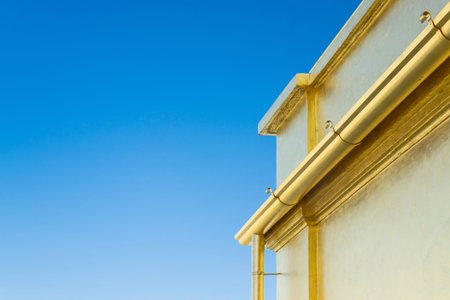 Detail of a building painted gold color on a background of blue sky.