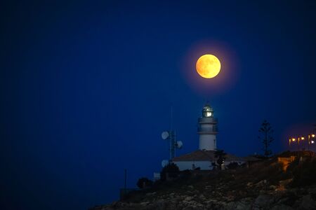 moon eclipse over a lighthouse on the coastの写真素材
