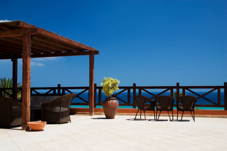 Balcony with 3 rattan chairs and ocean at the backgroundの写真素材