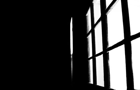 A black and white image of light coming from a windowの写真素材