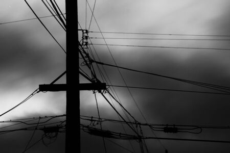 a telephone pole and power lines against a dramatic sky black and whiteの写真素材