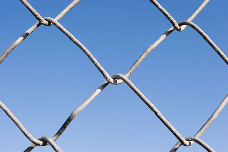 Closeup of a chin link fence with blue sky in the background