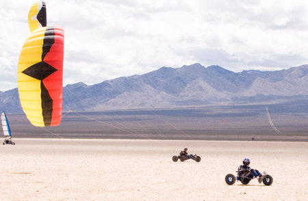 Two kite buggy pilots ride across a dry lakebedの写真素材