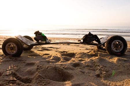 A mountainboard sits on a sandy beach at sunsetの写真素材
