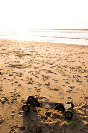 A mountainboard sits on a sandy beach at sunsetの写真素材
