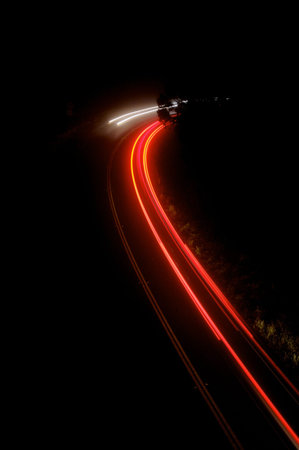 Long exposure showing the blur of passing cars on mountain road on a foggy night