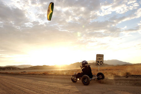 A man kite buggies on a deserted desert road at sunsetの写真素材