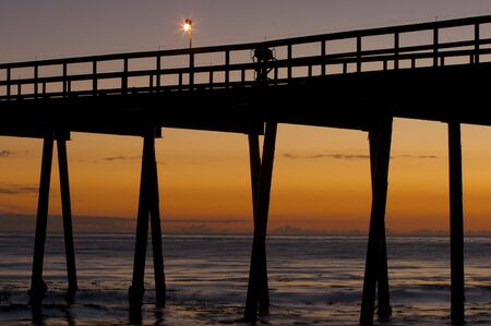 A Pier silhouetted at sunsetの写真素材