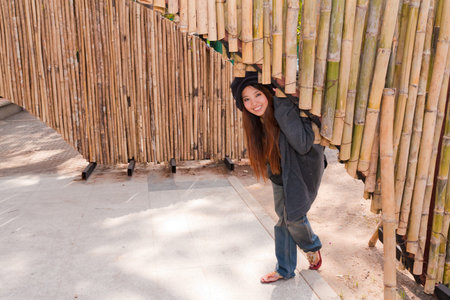 young woman is bending under bamboo arch and smile with relax feelingの写真素材