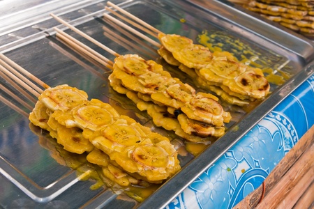 Grilled bananas stack with sticks with sweet sauce on metal plateの写真素材