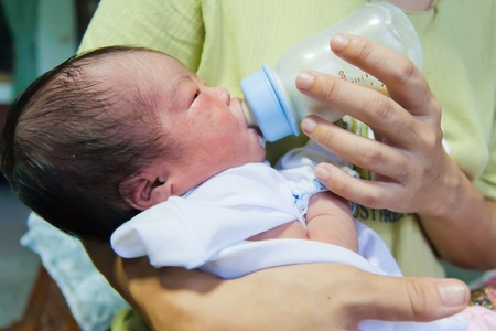 Asian female newborn eating milk from bottleの写真素材