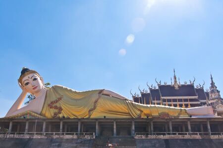 Reclining Buddha statue with blue sky and sun rayの写真素材