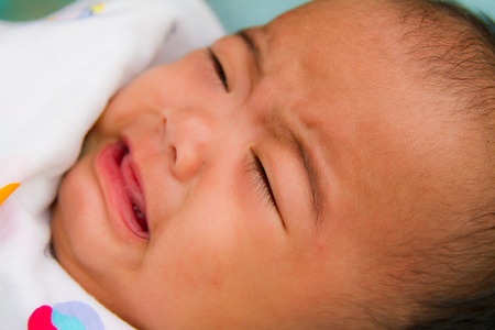 Crying Asian baby face close up on bedの写真素材