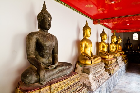 Black Buddha statue among other golden statue in temple in thailandのeditorial素材