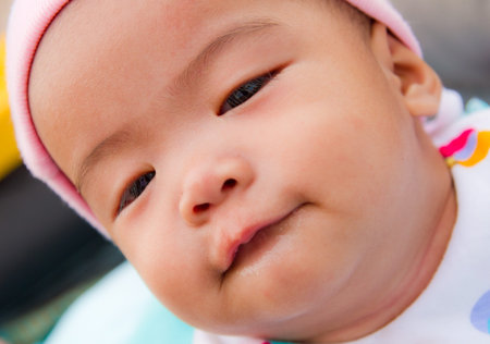 Asian baby bite her one lip on bed