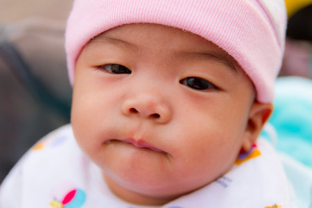 Asian baby bite her one lip on bed
