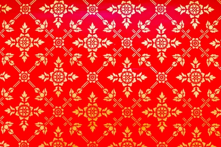 Golden Thai pattern on red wall decoration in templeの写真素材