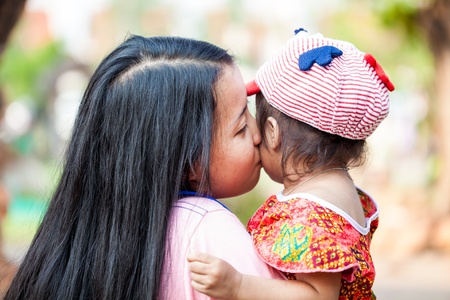 Asian woman holding and kissing her daughterの写真素材